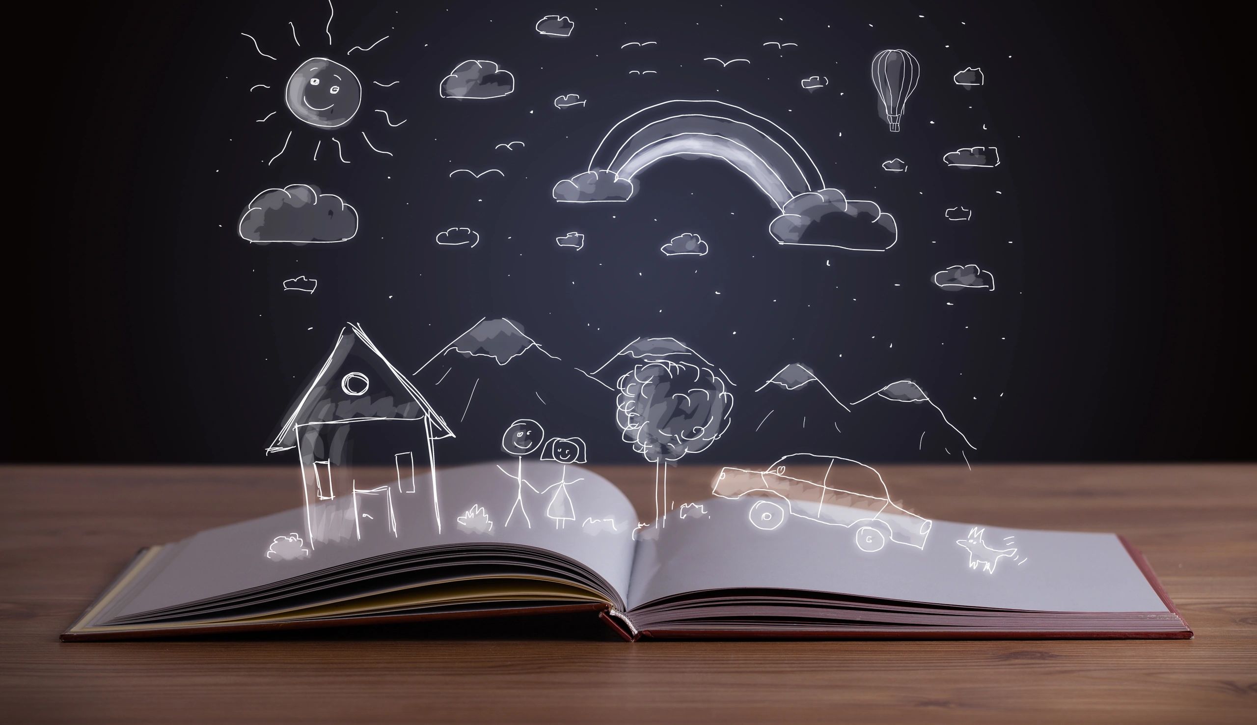 Open book with magical chalk drawings of a house, rainbow, and stars.